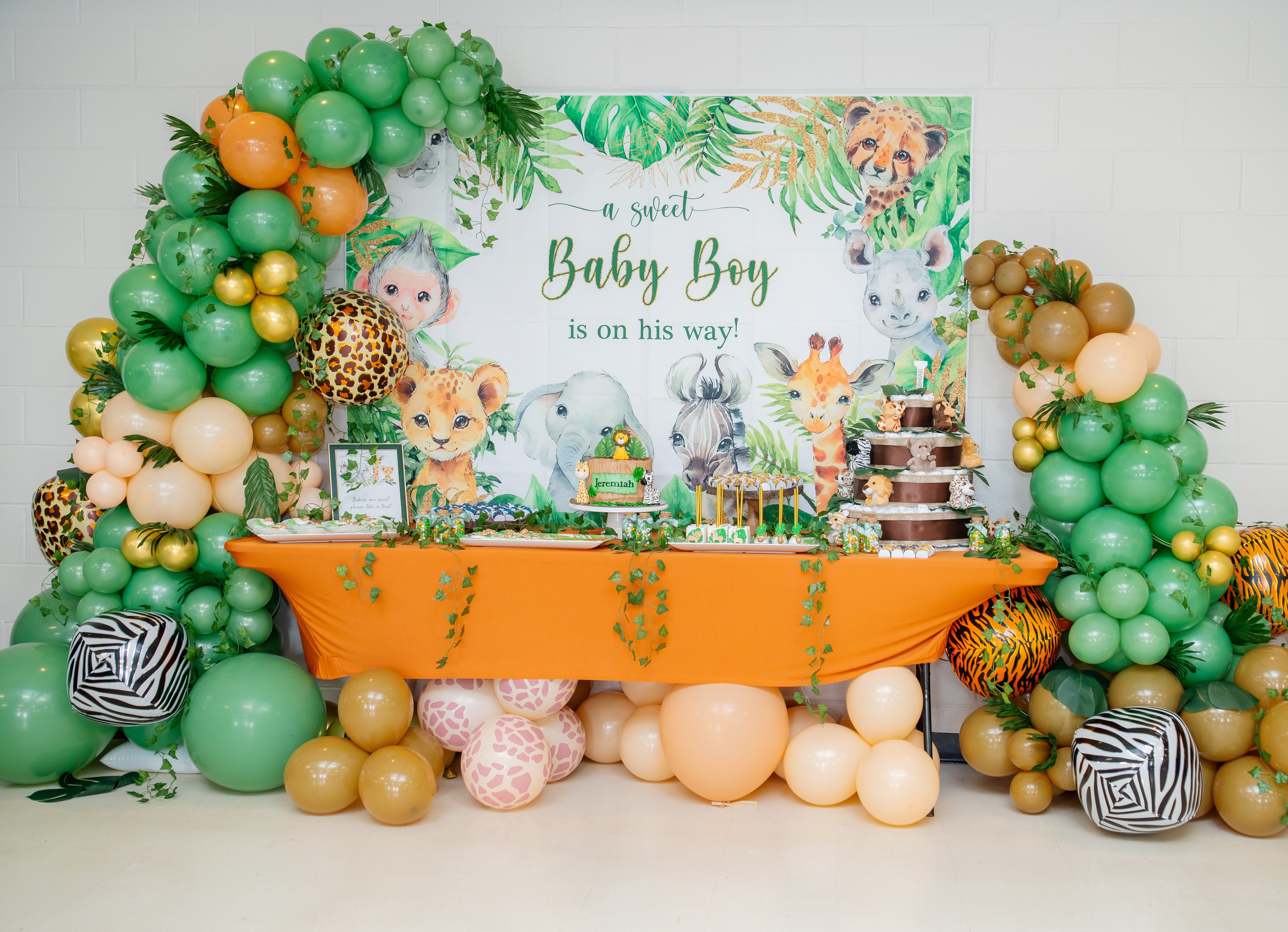 Safari themed baby boy shower dessert table with jungle balloon arch