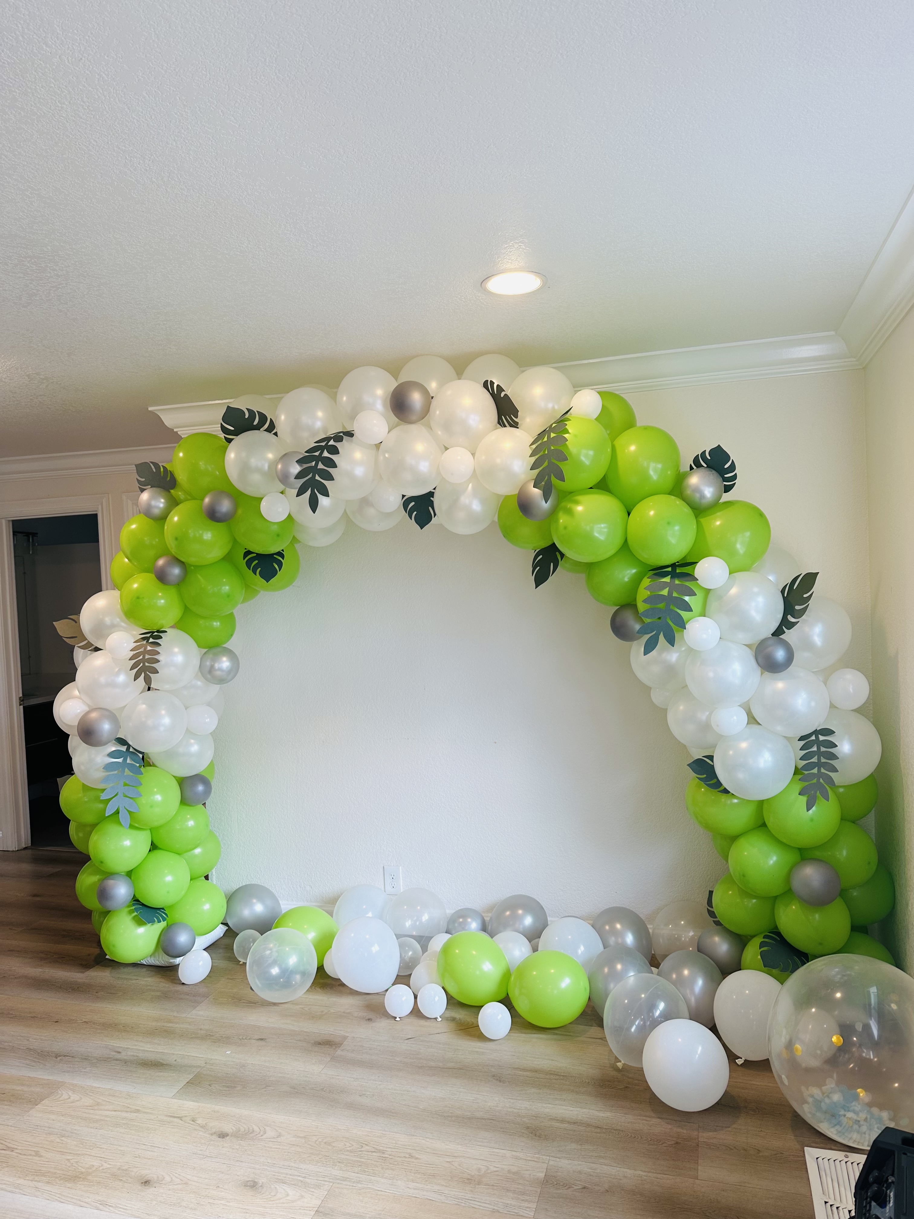 Tropical green, white, and silver full circle balloon arch with leaf accents