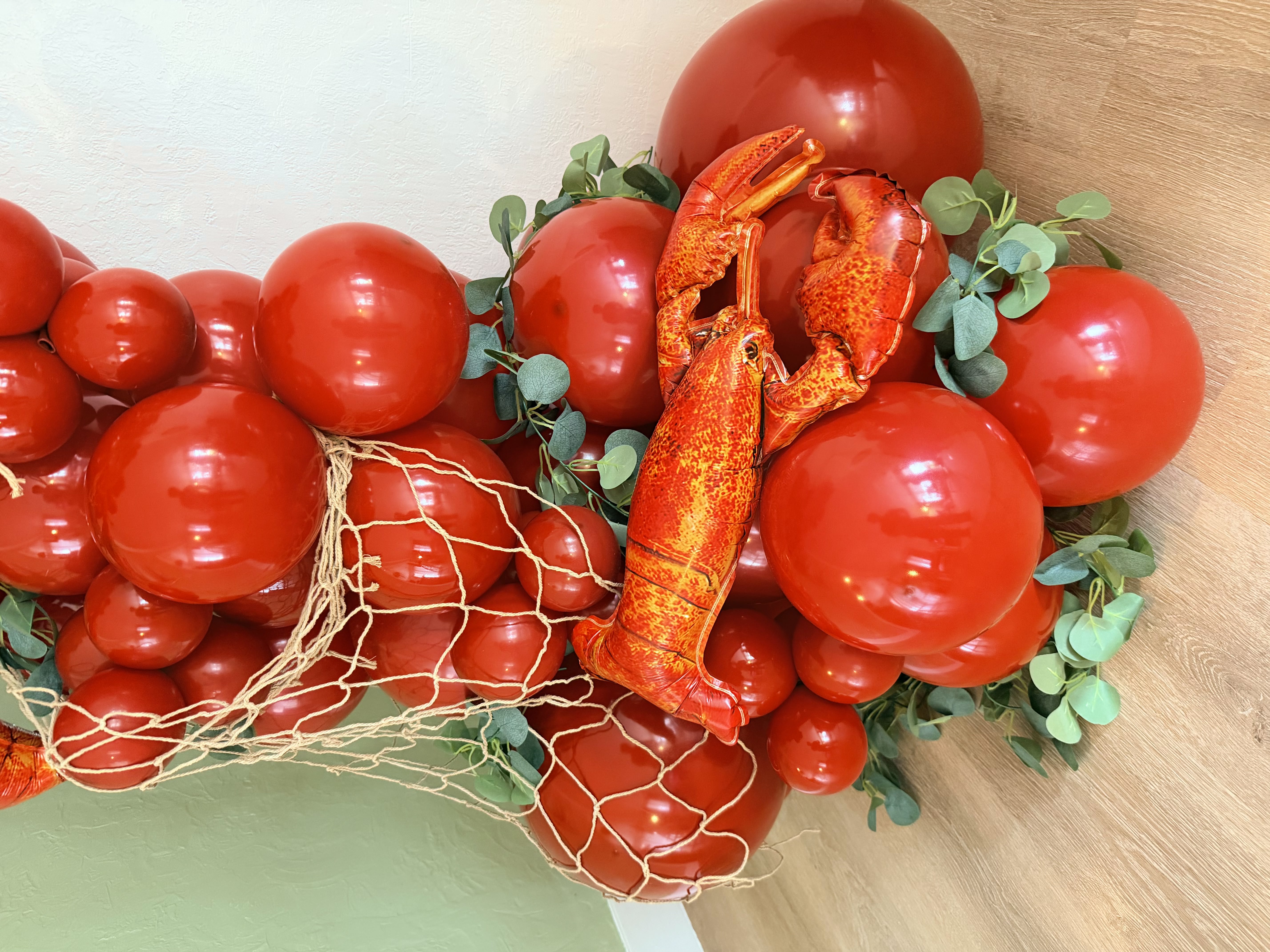 Close-up detail of lobster balloon garland with netting and eucalyptus