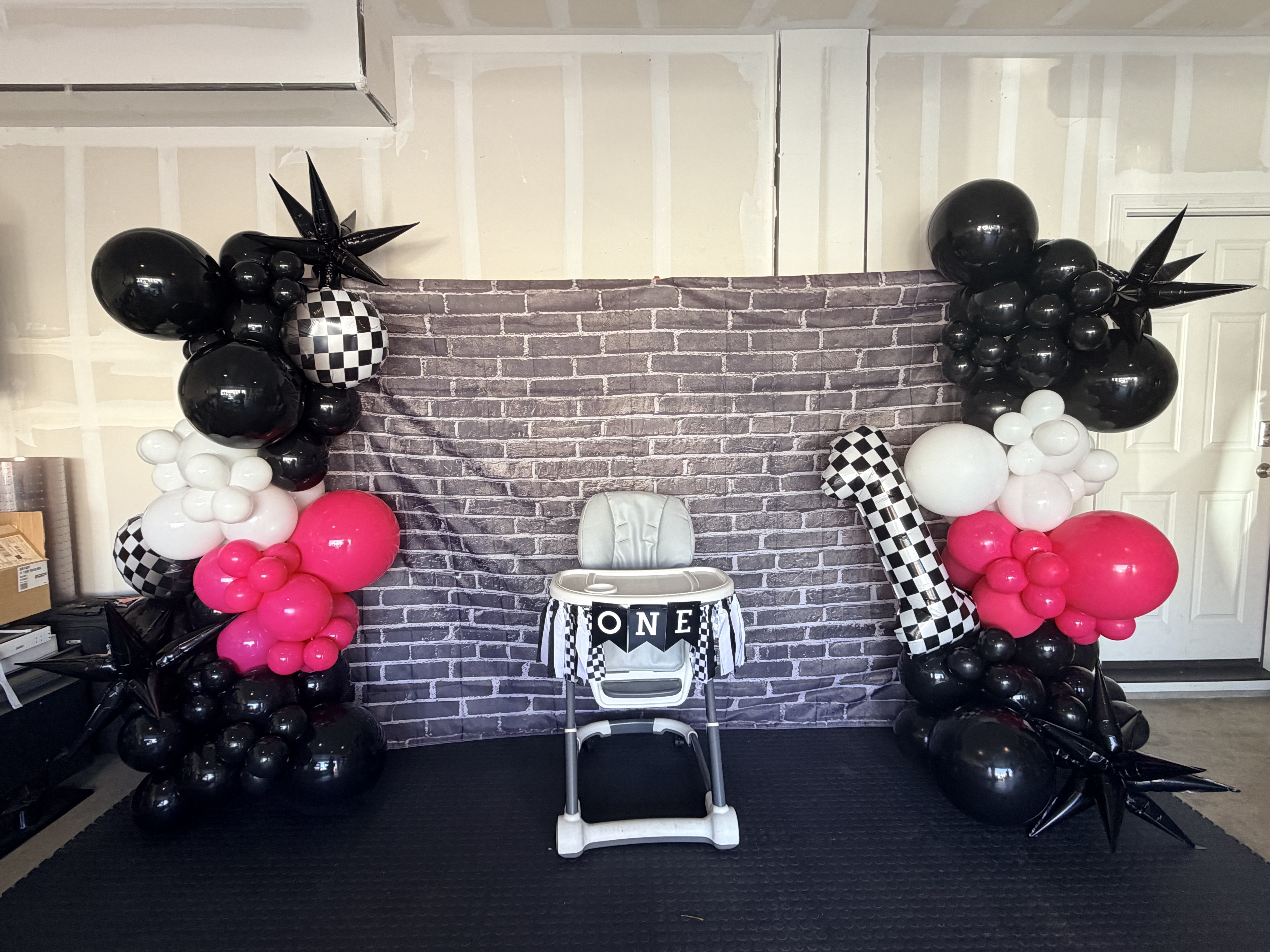 Race car themed balloon arch with high chair for first birthday